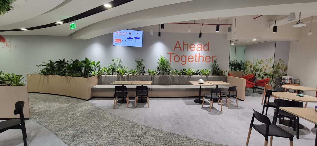 GSK office breakout area with botanical wall panels and hanging greenery, Bengaluru