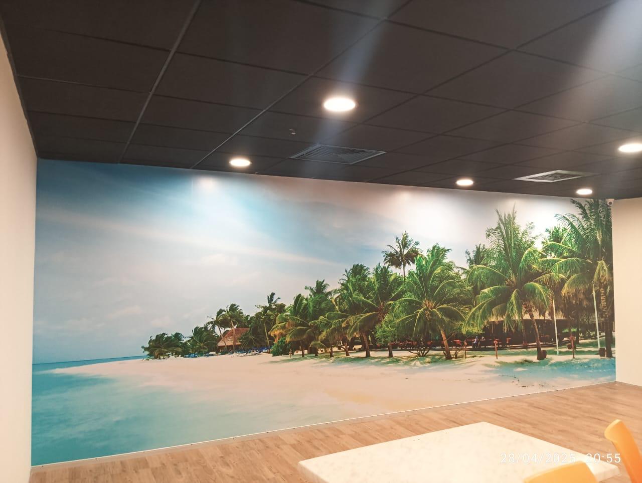 Break area with a beach-mural feature wall in the Home Credit office, Bengaluru