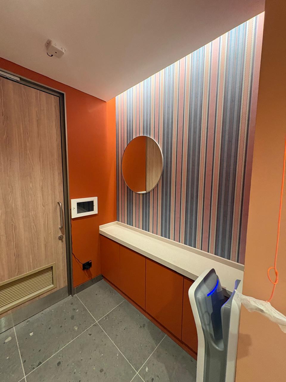 Intuit Bengaluru washroom interior detail with warm wood and burnt-orange walls