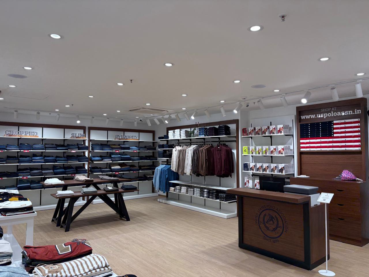 Denim wall and dark wood checkout counter with the USPA badge inside the U.S. Polo Assn. store in Bengaluru